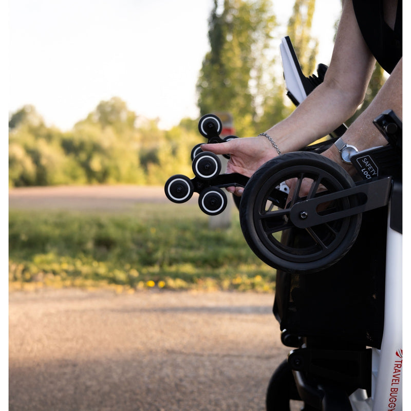 Hand holding the built-in loading wheels on a folded Travel Buggy Grand Tourer